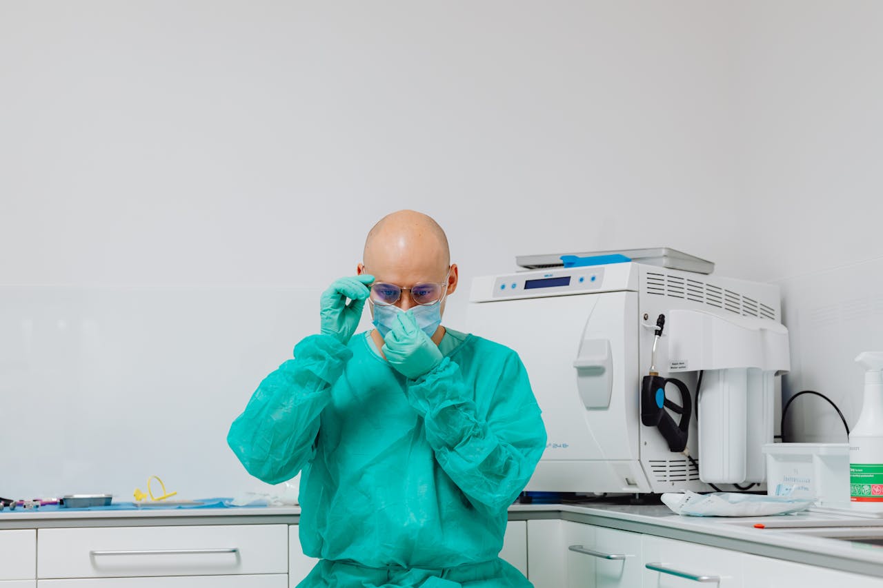 Bald medical practitioner adjusting face mask in a laboratory setting, focused on safety.